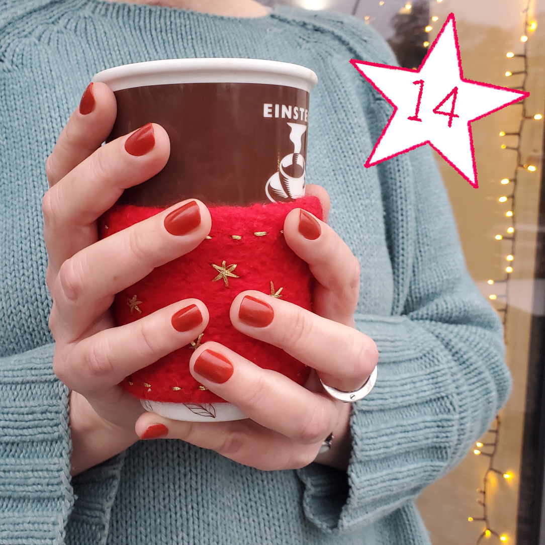 Modell hält Kaffeebecher mit roter, gefilzter Manschette
